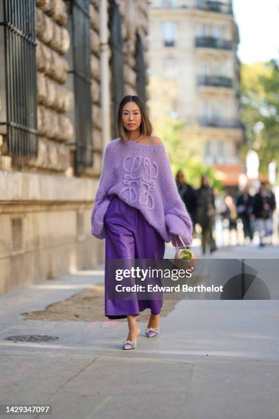 Aimee Song wears gold and pearl pendant earrings, a white pearls necklace, a pale purple wool with embroidered large logo oversized pullover from...