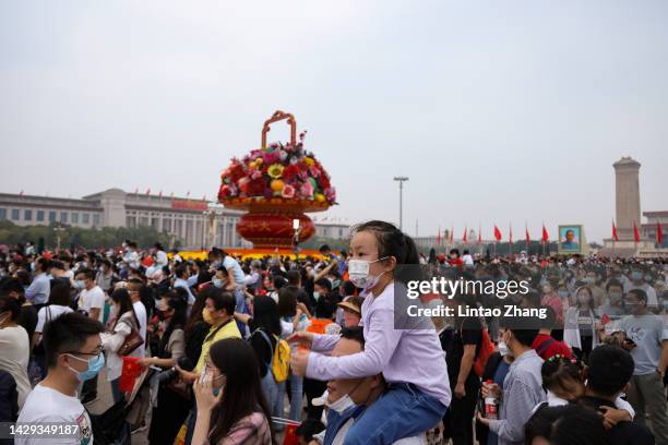 Child sits on the shoulders of a man as they watch the flag-raising ceremony at Tiananmen Square to celebration of the 73rd anniversary of of the...