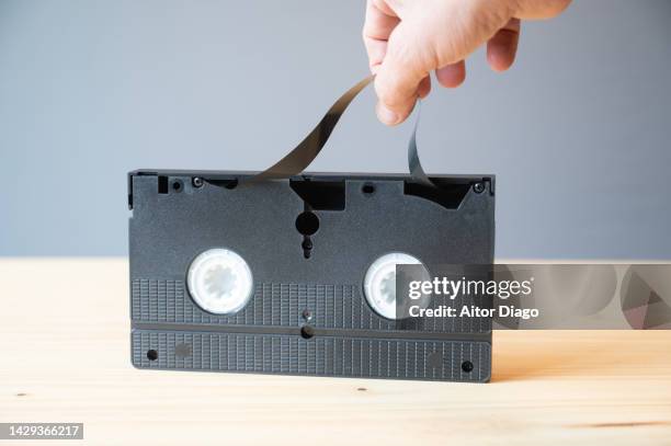 a person is going to try to repair a broken take a video tape which is  on a wood table. - video stock-fotos und bilder