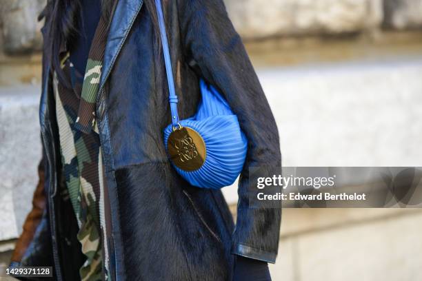 Guest wears a black turtleneck pullover, a black long coat, a khaki / brown / beige military print pattern long dress, a royal blue shiny leather...