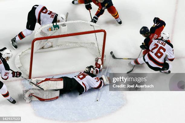 Goaltender Martin Brodeur dives to his left as Patrik Elias of the New Jersey Devils helps defend against Stephen Weiss of the Florida Panthers in...