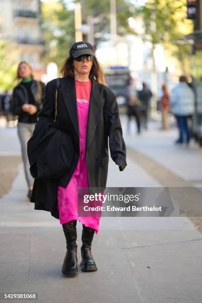 Guest wears a black with embroidered white "Paris" slogan cap, black futurist sunglasses, a red with white print pattern sweater, a neon pink silk...