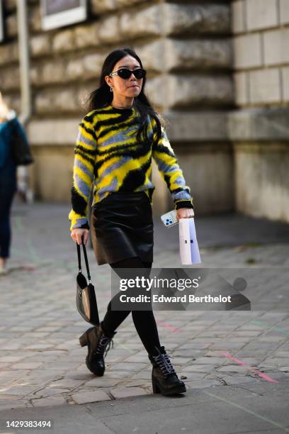 Guest wears black sunglasses, a black / yellow / gray zebra print pattern wool fluffy pullover, black tights, a black shiny leather short skirt, a...