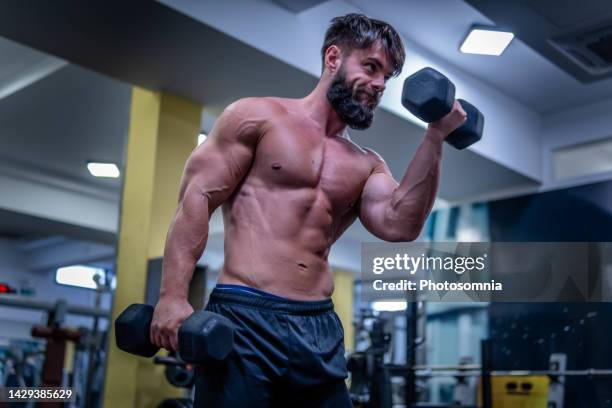 working on his biceps - bodybuilder flexing biceps stock pictures, royalty-free photos & images