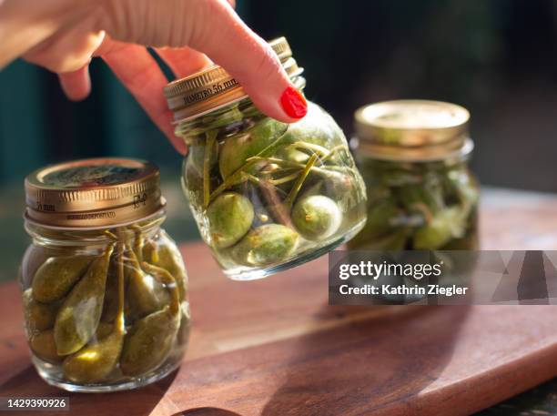 woman setting down jars with pickled caper berries - kapris bildbanksfoton och bilder