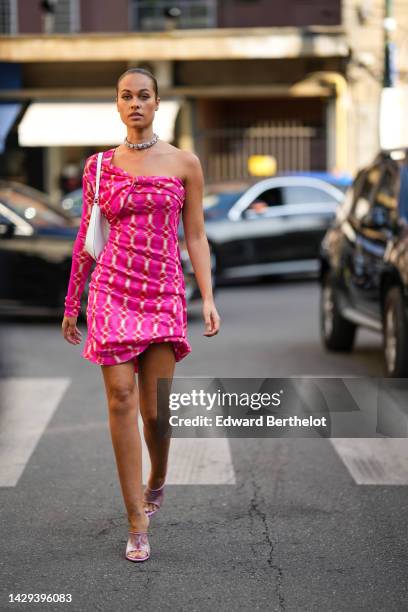 Sarah Lysander wears a large white and pink diamonds necklace, a red / pink / white print pattern one long sleeves / asymmetric shoulder-off / short...