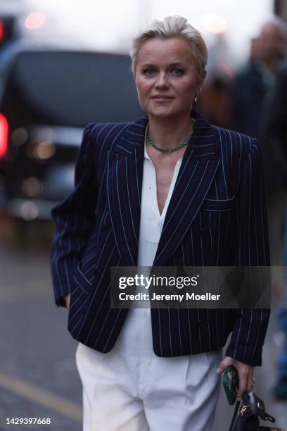 Barbara Sturm seen wearing a black Hermes mini Kelly bag, blue and white blazer, white suit and white boots outside Alessandra Rich during Pariser...