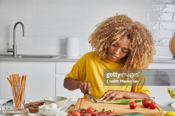 a woman slicing a young onion on the kitchen table - chopping stock pictures, royalty-free photos & images