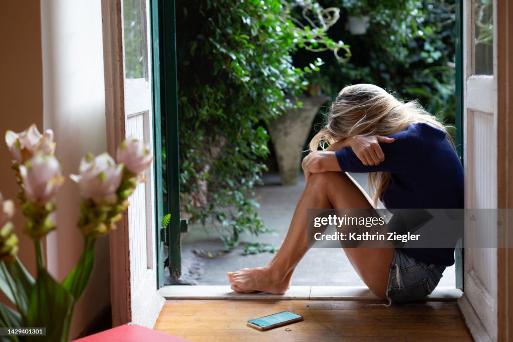 Woman crouching down in despair with head on her knees