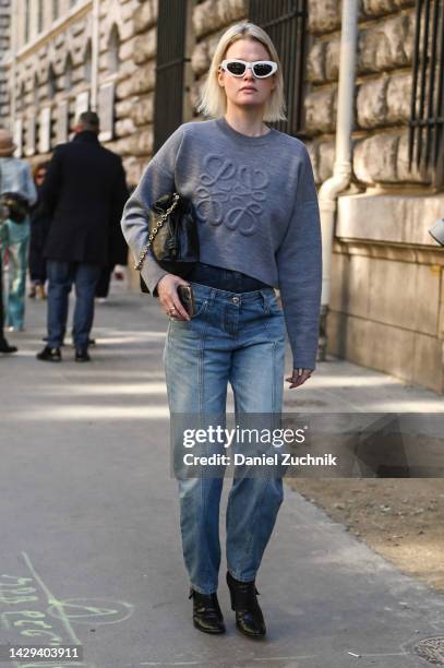 Guest is seen wearing a gray Loewe sweatshirt, black Loewe bag, blue jeans and white Loewe sunglasses outside the Loewe show during Paris Fashion...