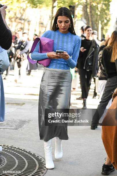 Guest is seen wearing. Blue top, gray skirt, white boots and purple bag outside the Loewe show during Paris Fashion Week S/S 2023 on September 30,...