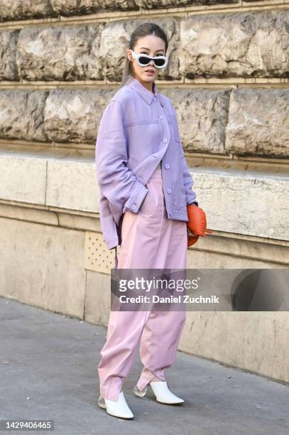 Jenny Tsang is seen wearing a purple Loewe shirt, pink Loewe pants, Loewe sunglasses and Loewe orange bag and white heels outside the Loewe show...