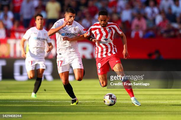 Matheus Cunha of Atletico de Madrid runs with the ball while under pressure from Erik Lamela of Sevilla FC during the LaLiga Santander match between...