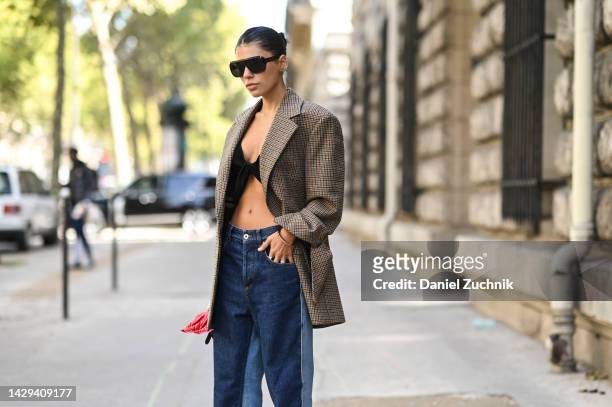 Jen Ceballos is seen wearing a plaid brown jacket, black top, blue jeans and sunglasses outside the Loewe show during Paris Fashion Week S/S 2023 on...