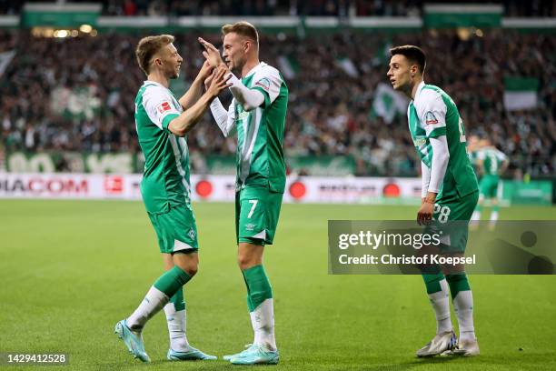 Mitchell Weiser and Marvin Ducksch of Werder Bremen celebrate their teams fourth goal, an own goal scored by Ramy Bensebaini of Borussia...