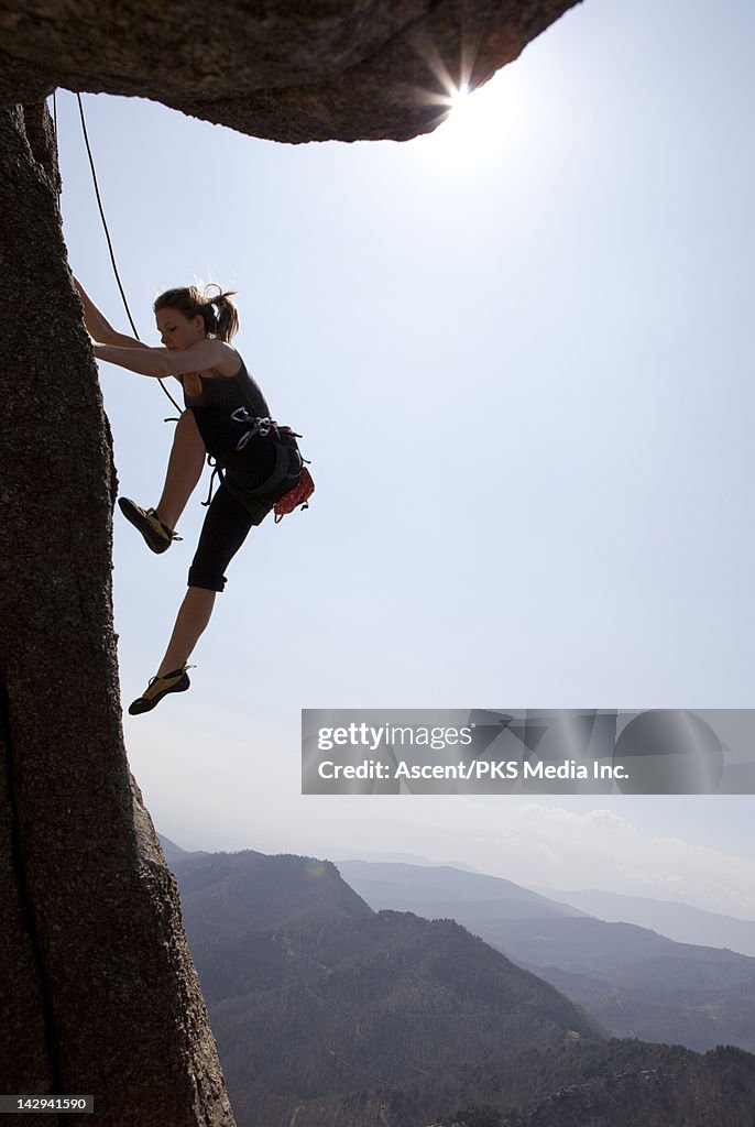 Teenage climber makes dynamic move on rock face