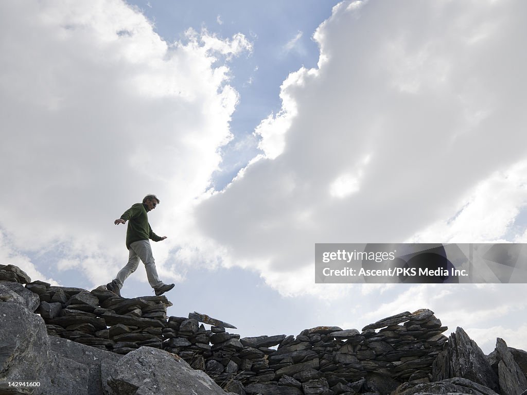 Man balances while walking on top of stone wall