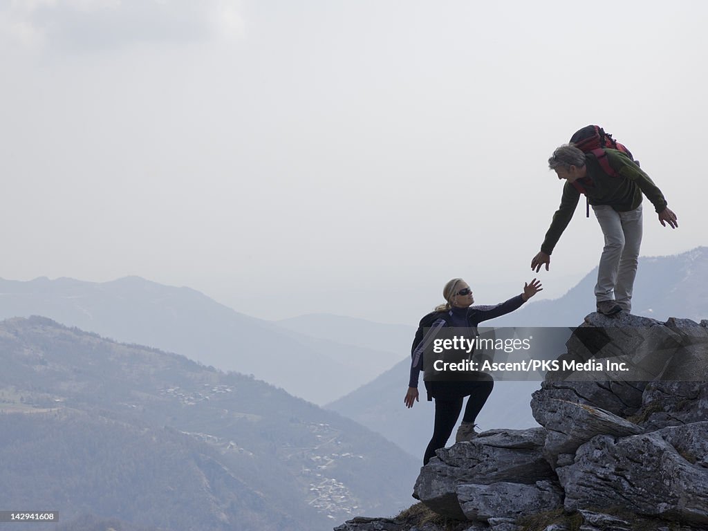 Hiker extends helping hand to partner, rock ridge