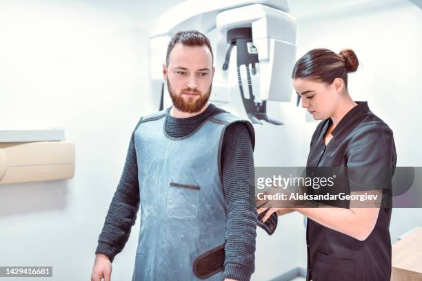 female dental radiologist preparing patient for scanning - vest stock pictures, royalty-free photos & images