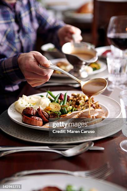 man pouring gravy onto turkey meal - sugo di carne foto e immagini stock