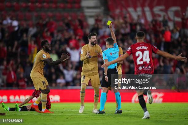 Gerard Pique of FC Barcelona is shown a yellow card by referee Jesus Gil Manzano during the LaLiga Santander match between RCD Mallorca and FC...