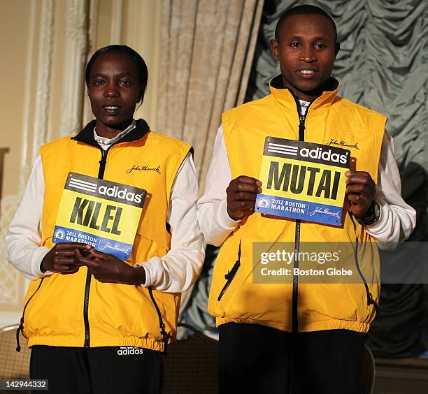 Boston Marathon winners Caroline Kilel, left, and Geoffrey Mutai, right, received their numbers for this year's race at a morning breakfast event.