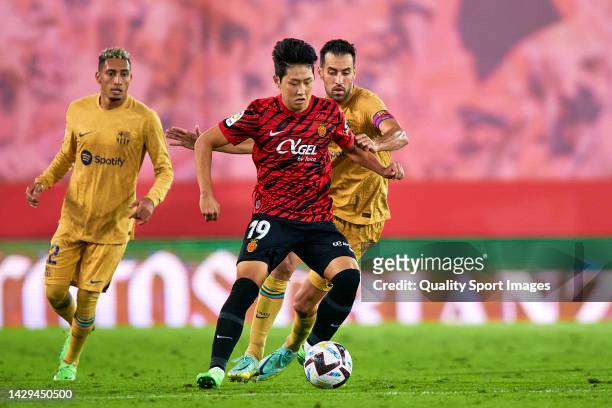 Kang-In Lee of Mallorca competes for the ball with Sergio Busquets of Barcelona during the LaLiga Santander match between RCD Mallorca and FC...