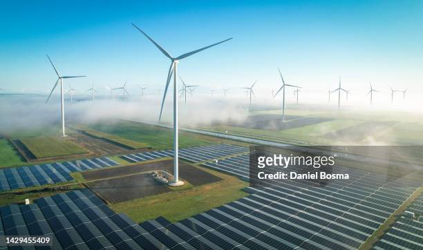 solar energy and wind turbines in fog, seen from the air - renewable energy stock-fotos und bilder