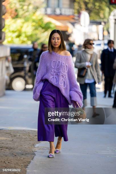Aimee Song wears purple oversized knit, wide leg pants, beige bag, heels outside Loewe during Paris Fashion Week - Womenswear Spring/Summer 2023 :...