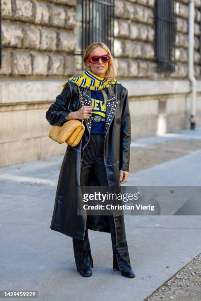 Blanca Miro Scrimieri wears black leather coat, yellow blue scarf, navy shirt, brown bag, striped pants outside Loewe during Paris Fashion Week -...