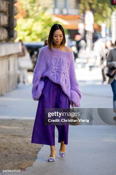 Aimee Song wears purple oversized knit, wide leg pants, beige bag, heels outside Loewe during Paris Fashion Week - Womenswear Spring/Summer 2023 :...