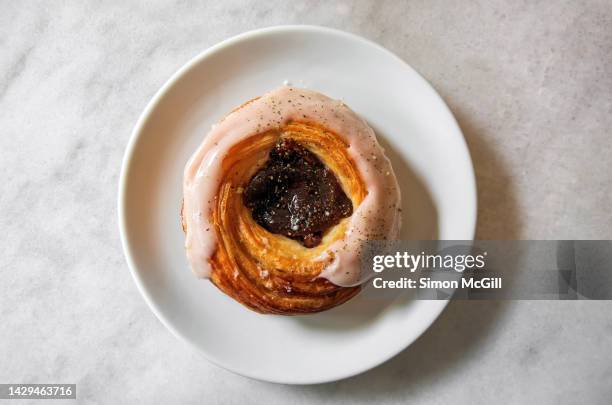 danés de higo y queso crema [fig and cream cheese danish] on a round white plate on a quartz cafe table - danish pastry stock pictures, royalty-free photos & images