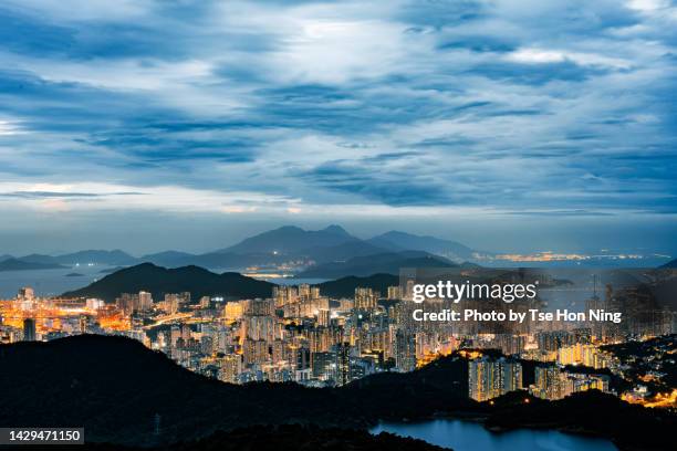 illuminating city downtown at dusk with mountains of lantau island at far - lantau imagens e fotografias de stock