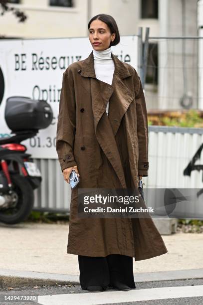 TyLynn Nguyen is seen wearing a brown trench coat, white turtleneck and black pants outside the Hermes show during Paris Fashion Week S/S 202 on...