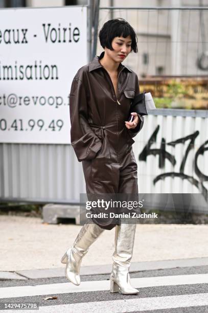 Guest is seen wearing a brown leather jumpsuit and gold boots outside the Hermes show during Paris Fashion Week S/S 202 on October 01, 2022 in Paris,...