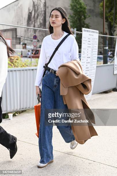 Model is seen wearing a white shirt, blue jeans, tan coat outside the Hermes show during Paris Fashion Week S/S 202 on October 01, 2022 in Paris,...