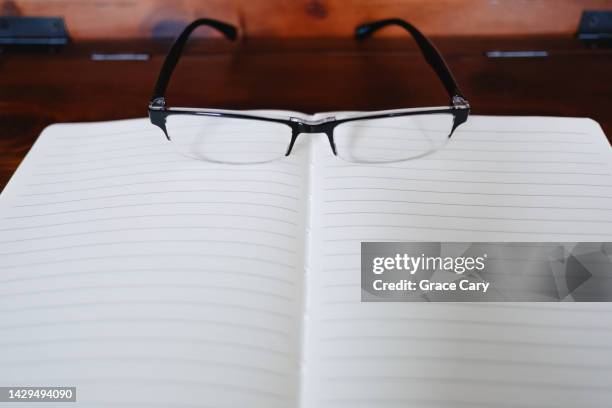 empty notebook with eyeglasses on desk - reading glasses on table stock pictures, royalty-free photos & images