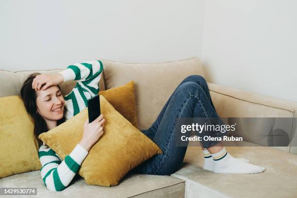 young woman lying on sofa with mobile phone. - sofa bed stock pictures, royalty-free photos & images