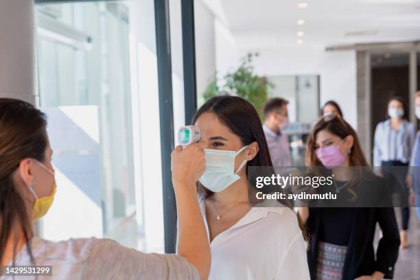 woman with gun thermometer cheking diverse people temperature in line - thermometer turkey stock pictures, royalty-free photos & images