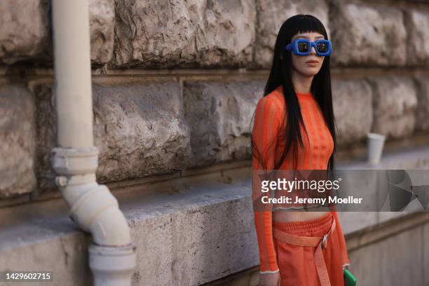 Irene Kim guest seen wearing a total orange Loewe look with blue Loewe sunglasses, outside Loewe during Paris Fashion Week on September 30, 2022 in...