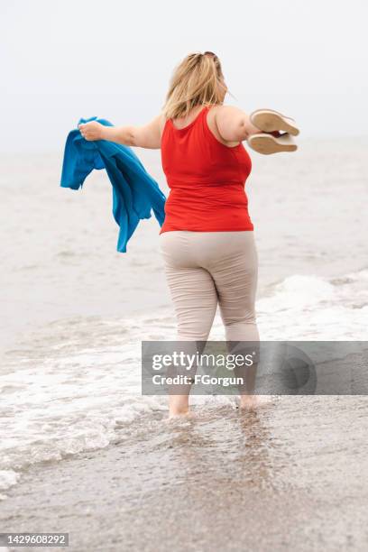 donna sovrappeso spiaggia aperto braccia croce - arms open foto e immagini stock