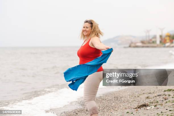 overweight woman dancing by the sea - fat woman dancing stockfoto's en -beelden