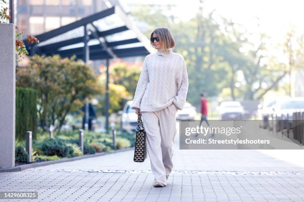 Influencer Gitta Banko, wearing a full look by Gitta Banko the Label, beige sneakers by Balenciaga, a black-beige patterned shopper bag by Prada and...