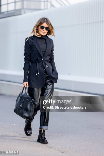 Influencer Gitta Banko, wearing a full look by Airfield, a black shopper bag by Saint Laurent, black boots by Saint Laurent and sunglasses by Ray...