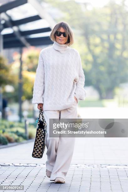 Influencer Gitta Banko, wearing a full look by Gitta Banko the Label, beige sneakers by Balenciaga, a black-beige patterned shopper bag by Prada and...