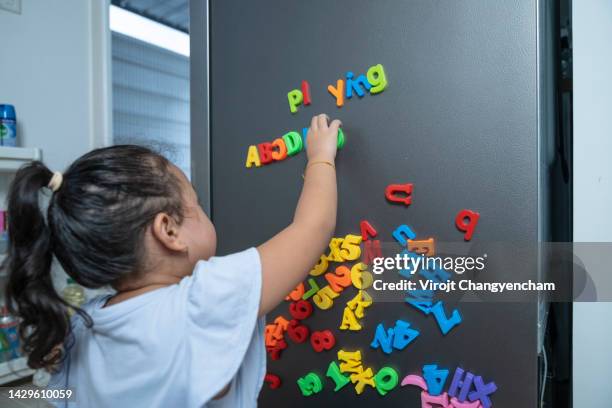 kid playing with magnet letters text on refrigerator - ordre alphabétique photos et images de collection