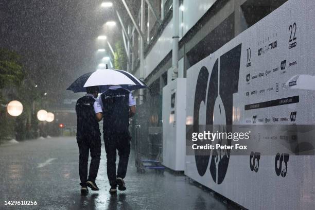 Rain falls as Scuderia AlphaTauri team members walk in the Paddock prior to the F1 Grand Prix of Singapore at Marina Bay Street Circuit on October...
