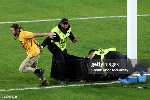 Pitch invaded removes padding from the goal posts during the 2022 NRL Grand Final match between the Penrith Panthers and the Parramatta Eels at Accor...