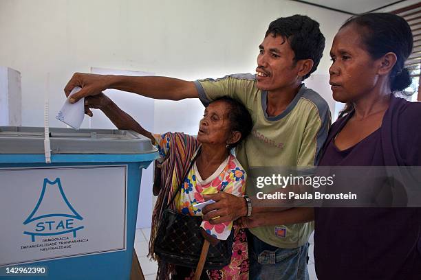 An East Timorese handicapped woman is assisted by her family, helping her vote in the run-off Presidential elections on April 16, 2012 in Dili, East...