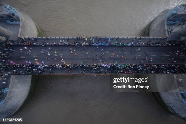 Runners cross Tower Bridge during the London Marathon on October 02, 2022 in London, England. The view is as seen from the high-level glass floor of...